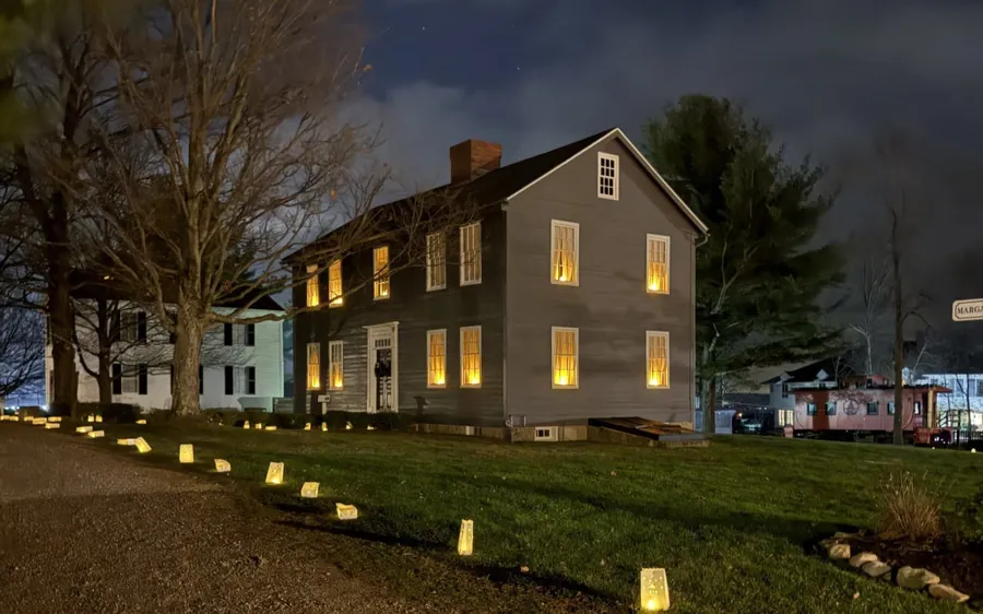 A historic village home lit by candle luminaries at dusk