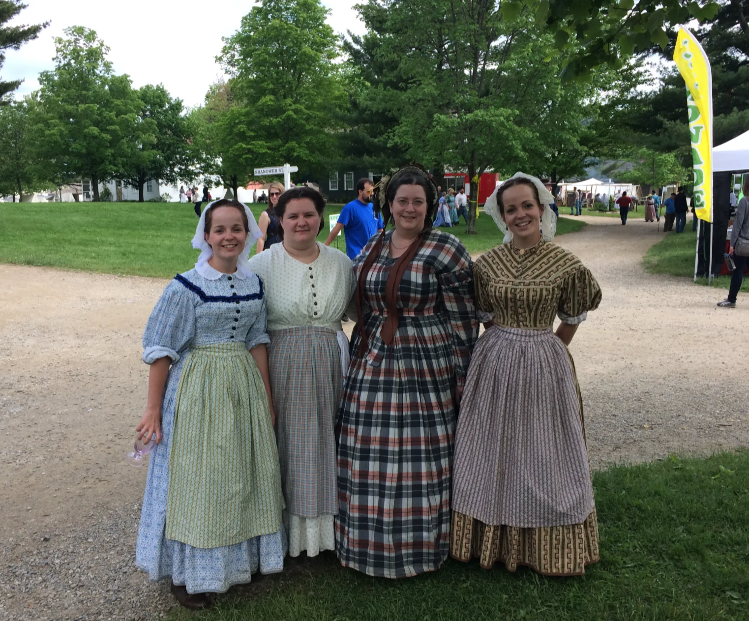 Four volunteers in period costume at the village during a festival.